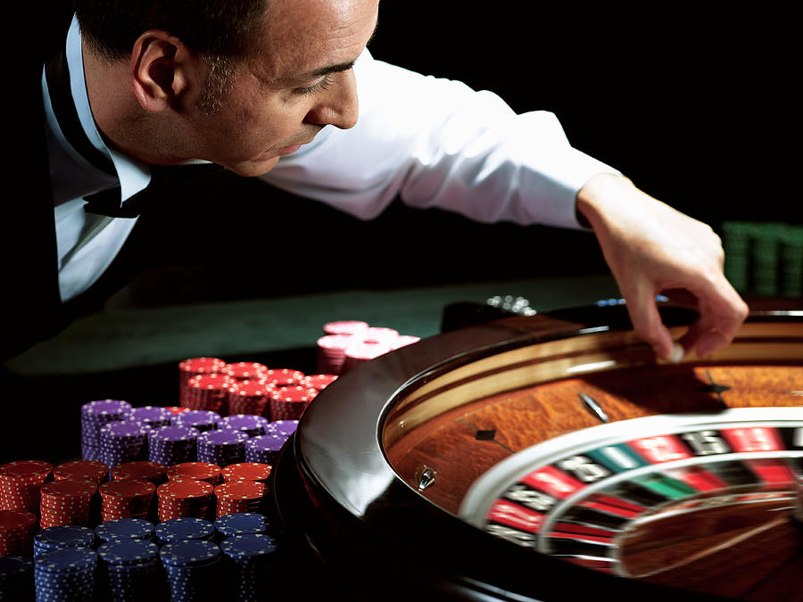Male croupier placing ball on roulette wheel (blurred motion) Photograph by John Howard