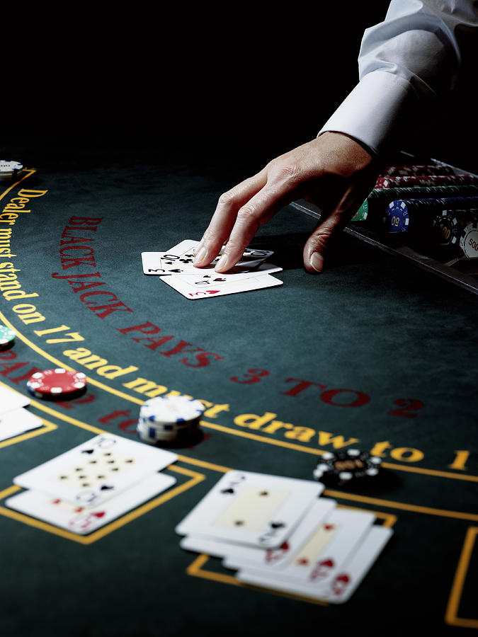 Male croupier resting hand on upturned cards on gaming table Photograph by John Howard
