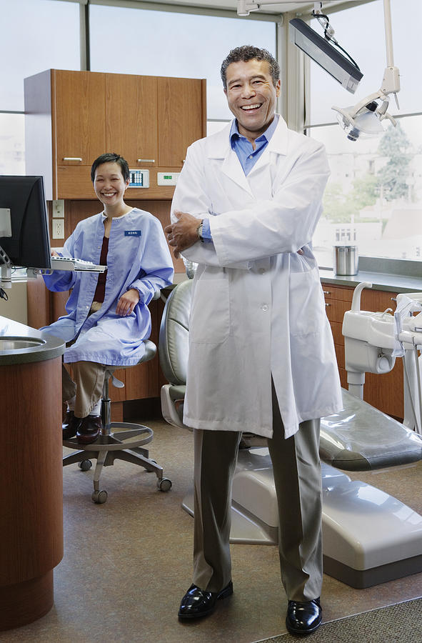 Male dentist and female dental assistant in examination room, portrait Photograph by Andersen Ross