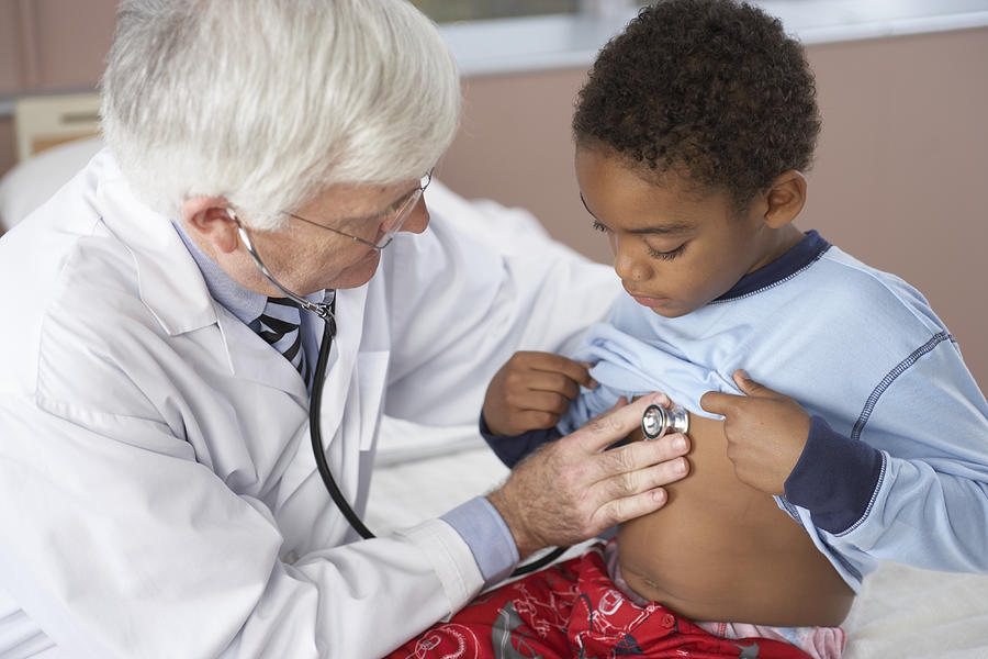 Male doctor examining boy (6-7) with stethoscope, close-up Photograph by Darrin Klimek