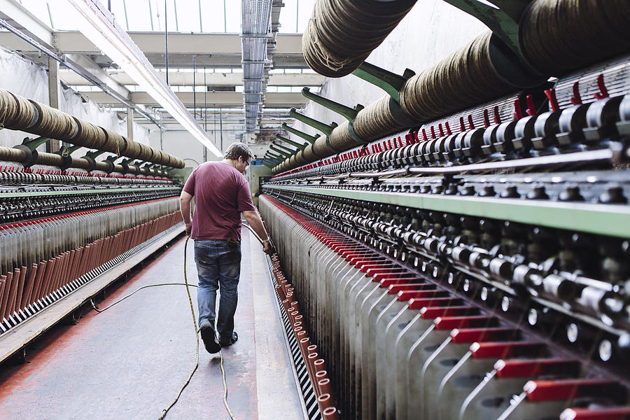 Male factory worker monitoring weaving machines in woollen mill Photograph by Mark Webster