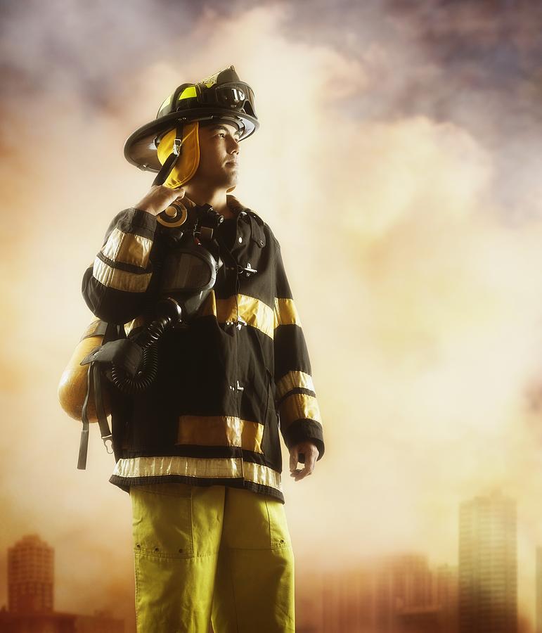 Male fire fighter with smoky background Photograph by Colin Anderson Productions pty ltd