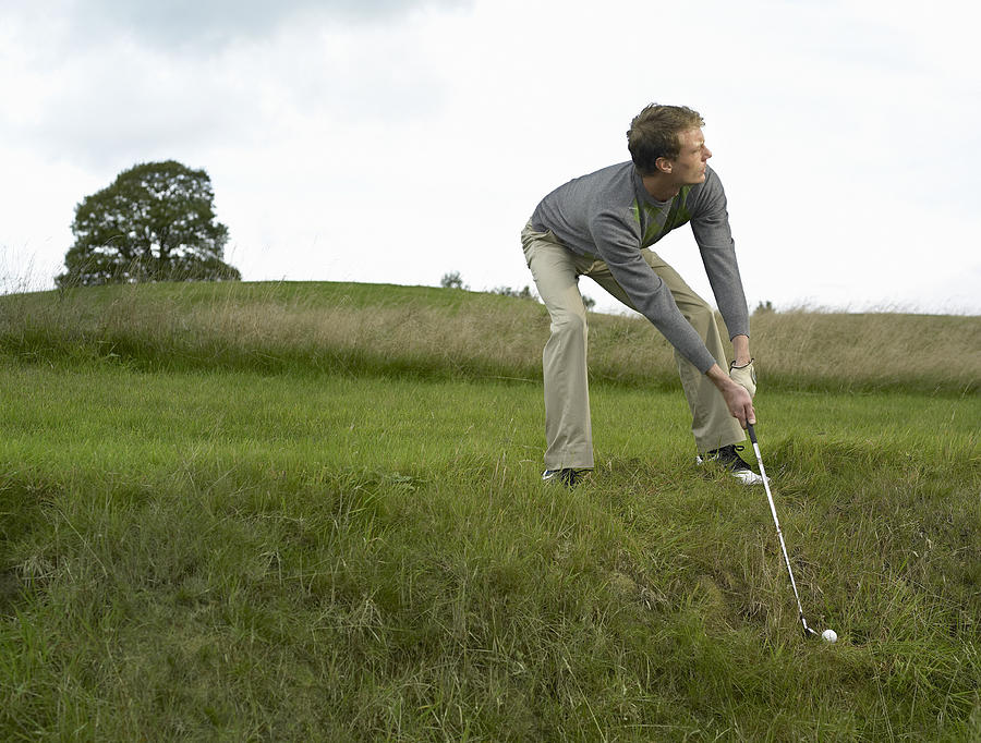 Male golfer preparing to hit ball out of ditch Photograph by Alan Thornton