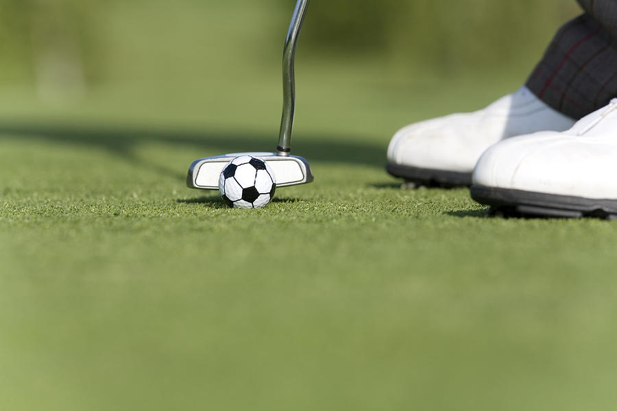 Male golfer putting soccer golf ball on green, low section, close up Photograph by Photo and Co