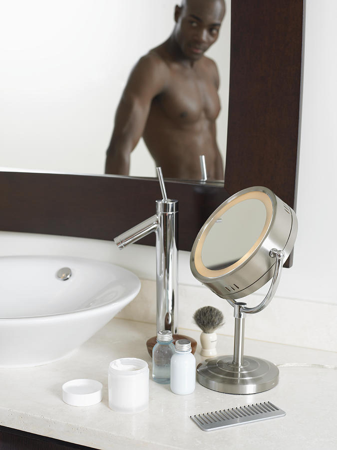 Male Grooming Accessories in a Bathroom, Man Looking at His reflection in a Mirror Photograph by Digital Vision.