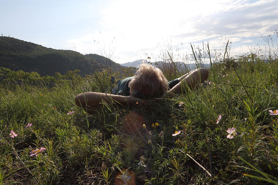 Male hiker relaxes in meadow above distant hills Photograph by Ascent/PKS Media Inc.