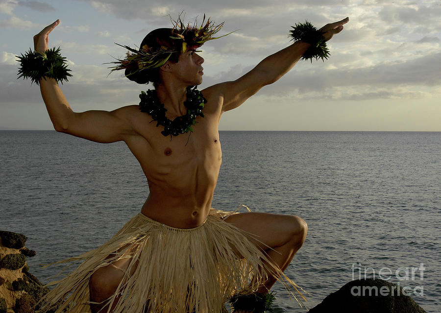 Male Hula Dancer poses on the beach and is almost silhouetted as the sun begins to set. Photograph by Gunther Allen