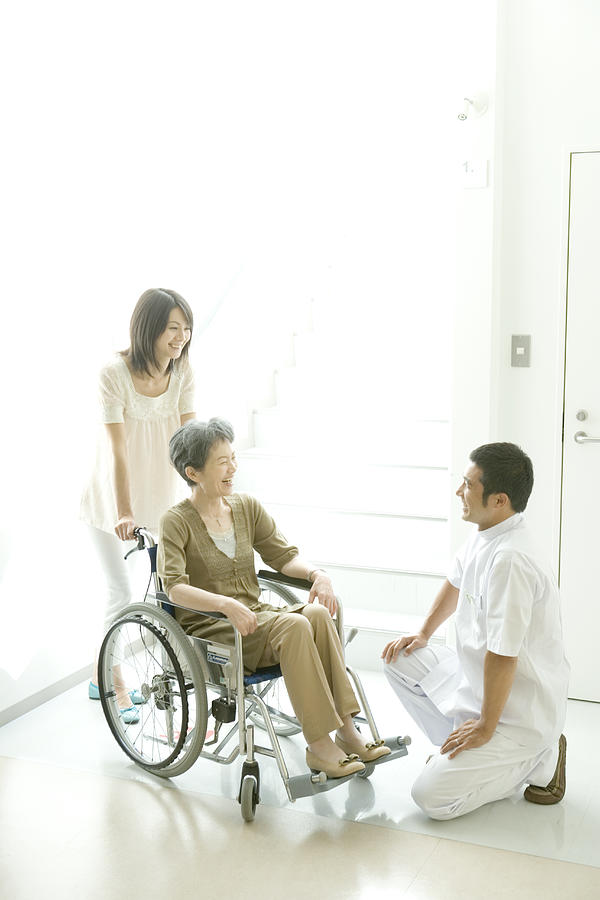 Male nurse kneeling to senior woman in wheel chair Photograph by Indeed