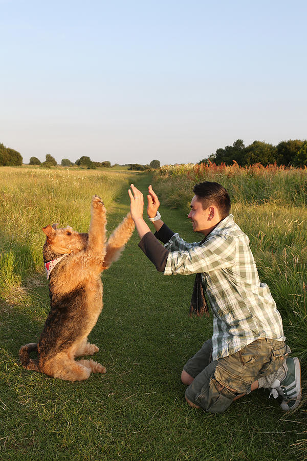 Male owner performing tricks with dog outside Photograph by Nicola Tree