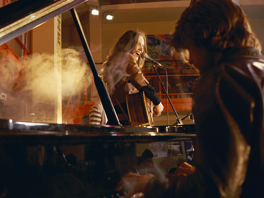 Male Pianist and a Female Guitarist Performing on a Smokey Stage Photograph by Digital Vision.