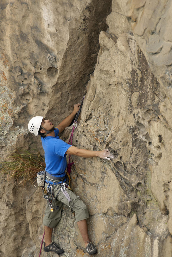 Male rock climber scaling a rock face Photograph by Glowimages