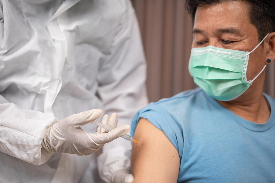 Male senior patient getting vaccinated at medical clinic during coronavirus pandemic. Photograph by Witthaya Prasongsin