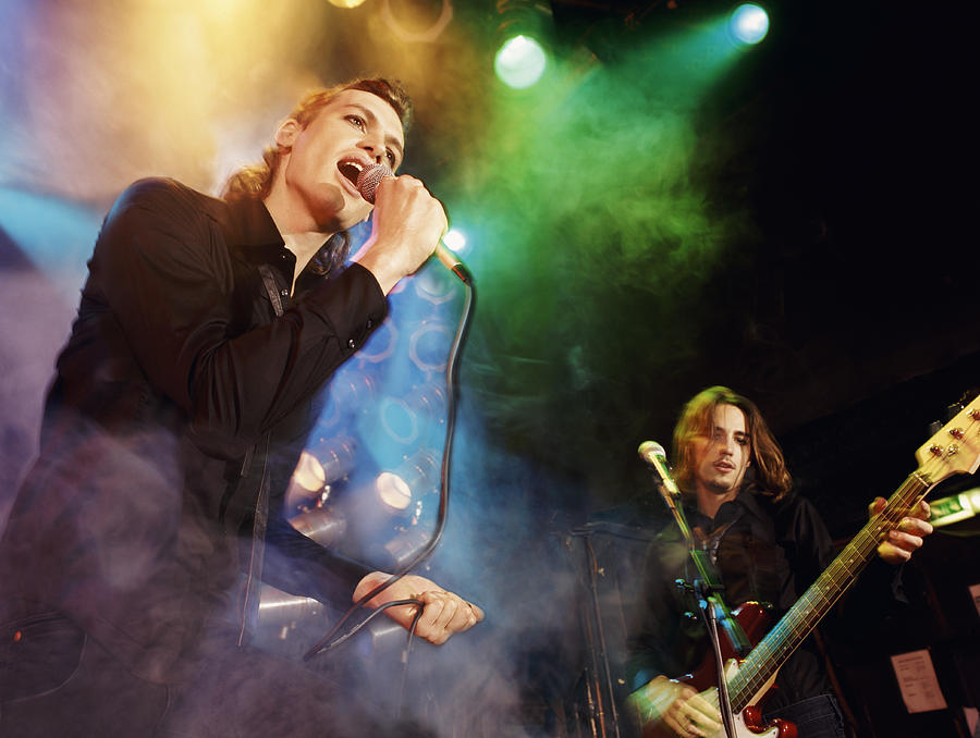 Male Singer and Guitarist in an Indie Band Perform on Smoky, Spotlit Stage Photograph by Digital Vision.
