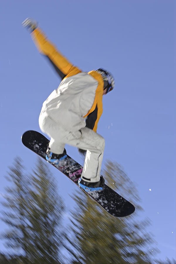 Male snowboarder in mid air, rear view (blurred motion) Photograph by Karl Weatherly