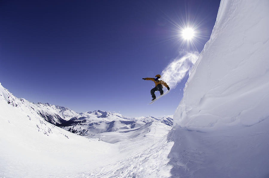 Male snowboarder jumping off cornice, low angle view Photograph by Darryl Leniuk