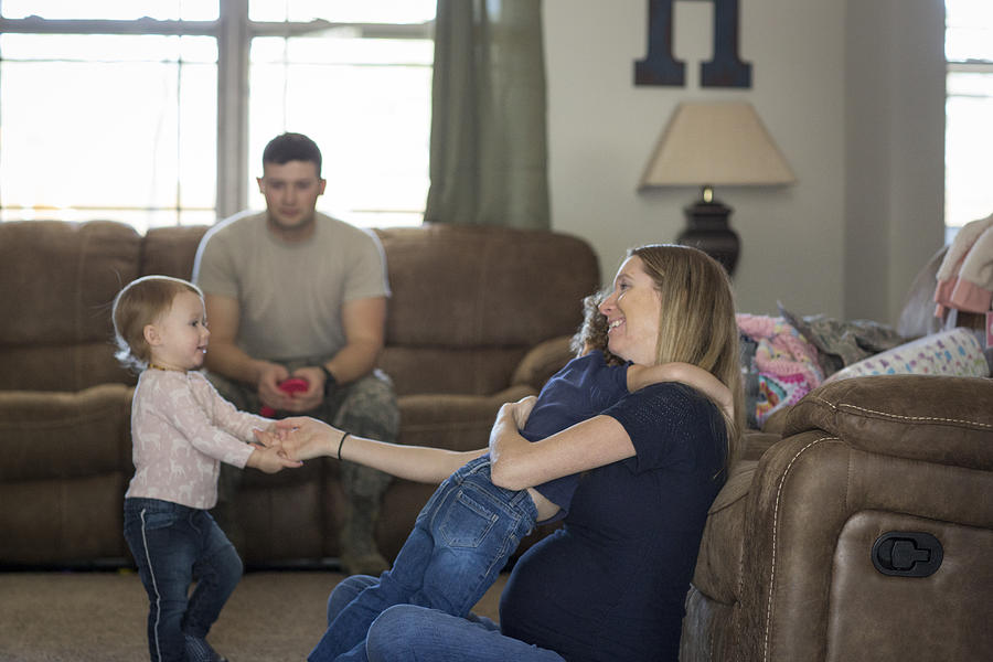 Male soldier and wife playing with daughters in living room at air force military base Photograph by Sean Murphy