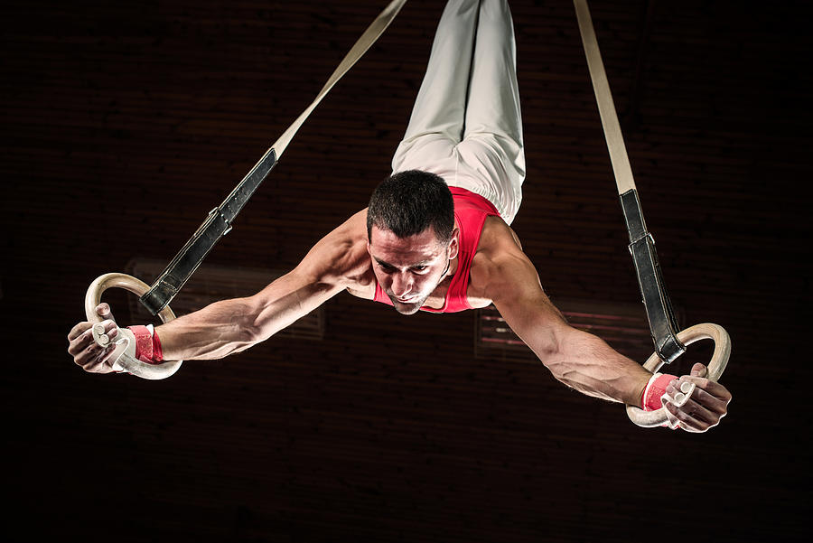Male sportsman on gymnastics rings. Photograph by Skynesher