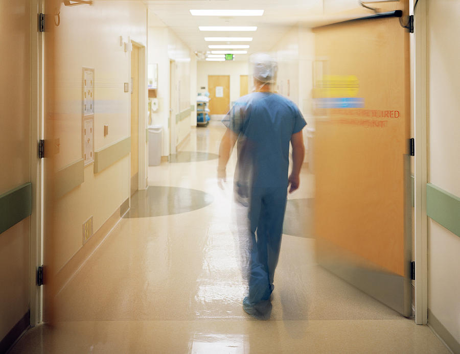 Male surgeon walking down corridor, rear view (blurred motion) Photograph by Ryan McVay