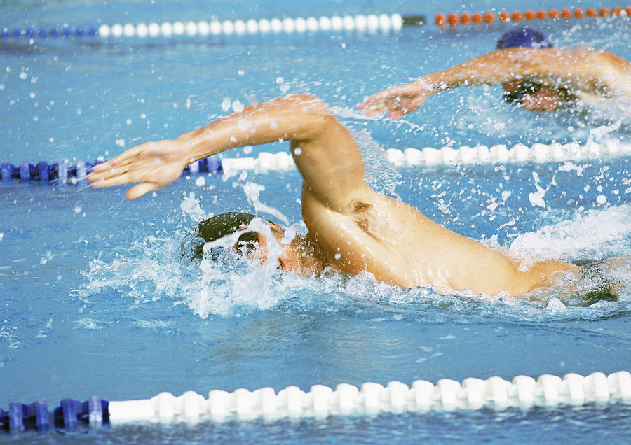 Male swimmers doing freestyle in pool, close-up Photograph by Teo Lannie