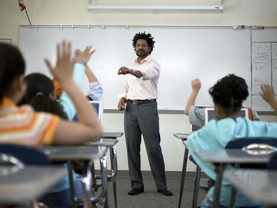 Male teacher standing before students (8-10) with hands raised Photograph by Thomas Barwick