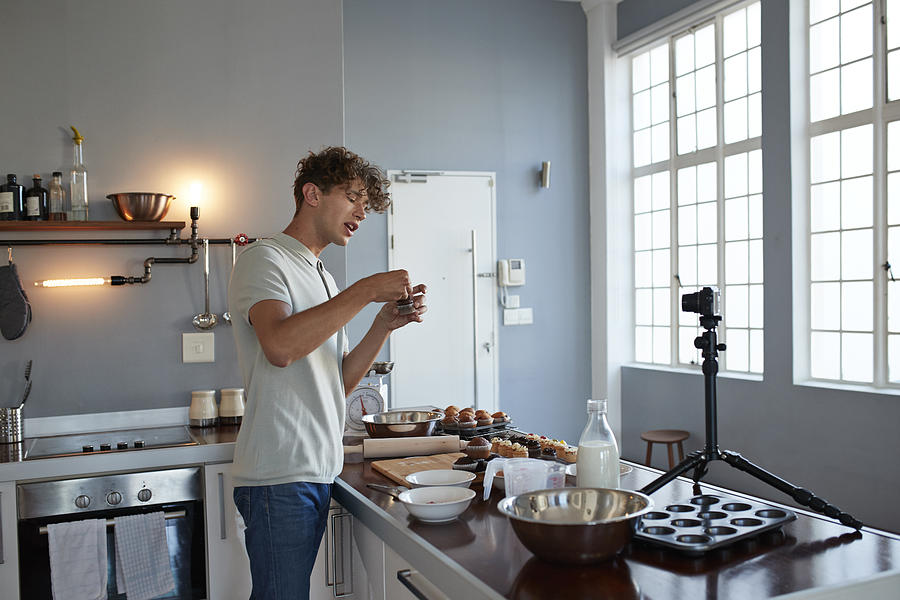 Male vlogger making video while baking in kitchen Photograph by Klaus Vedfelt