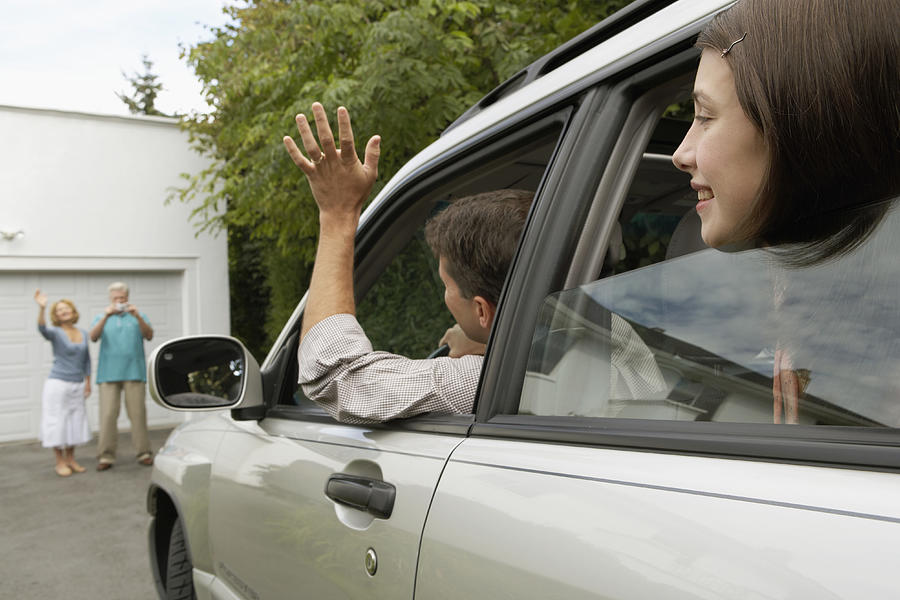 Man and daughter (13-15 years) in car waving to senior couple on drive Photograph by Noel Hendrickson