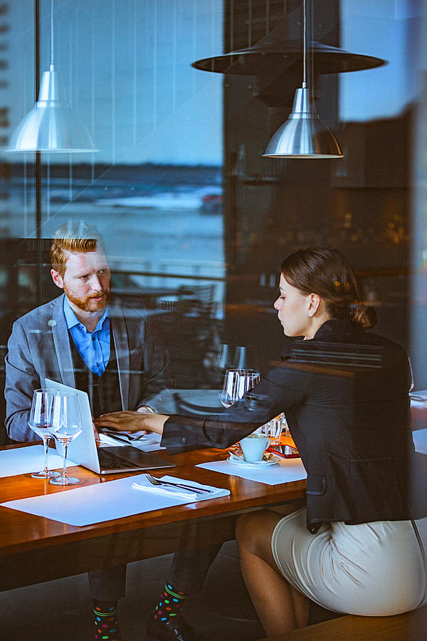 Man and Woman Having a Business Meeting During Lunch Time in a Cafe / Restaurant Photograph by Gruizza