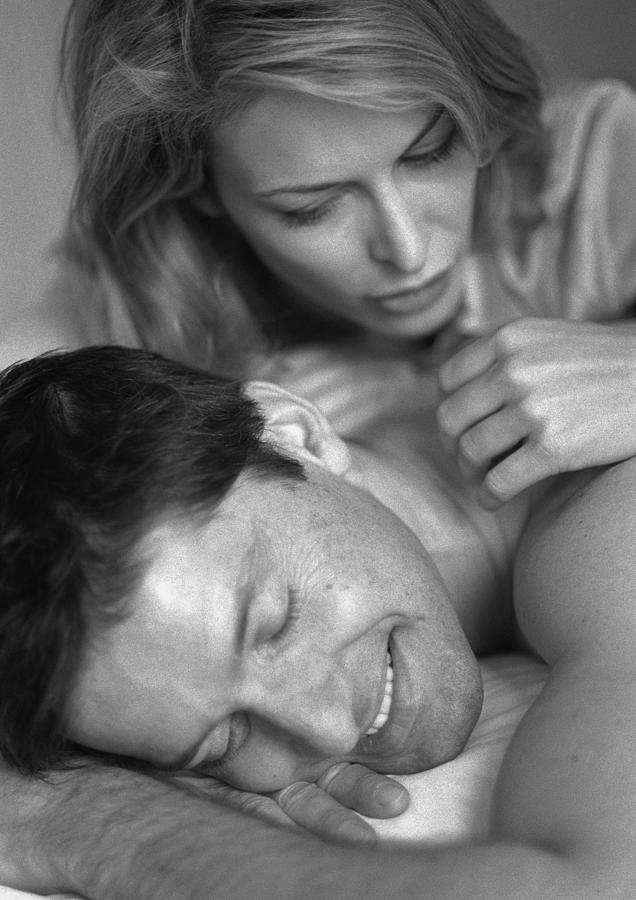 Man and woman laying on bed, close-up, b&w Photograph by Clara Neuimie