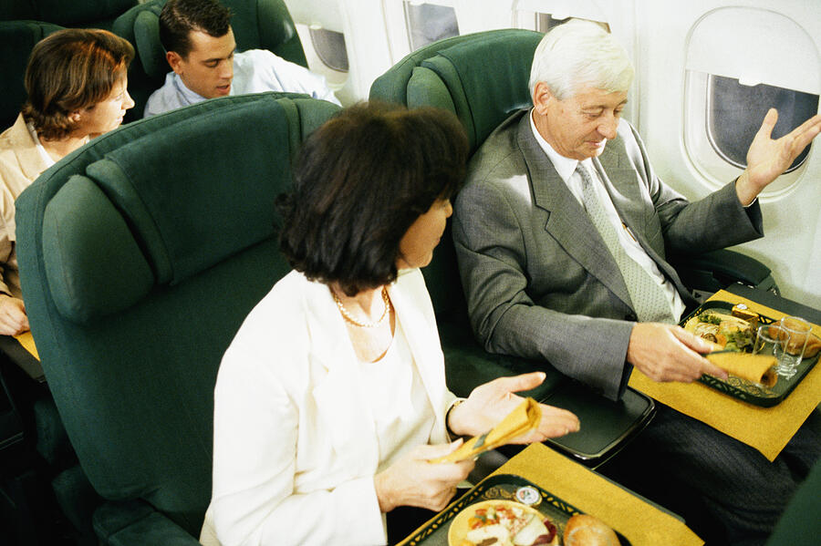 Man and woman on airplane having airline food Photograph by David De Lossy