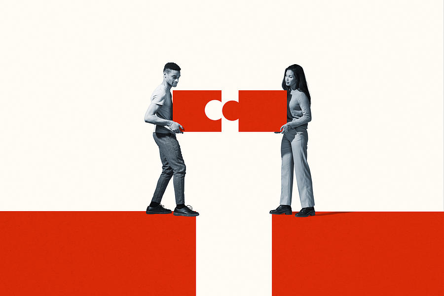 Man and woman positioning orange puzzle pieces Photograph by Klaus Vedfelt