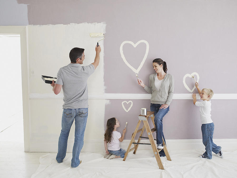 Man and woman with boy and girl painting hearts on wall Photograph by Chris Ryan