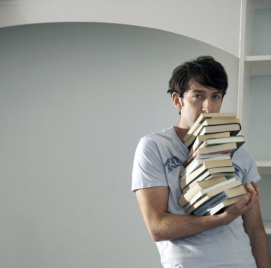 Man balancing big stack of books with one hand Photograph by Gary Houlder