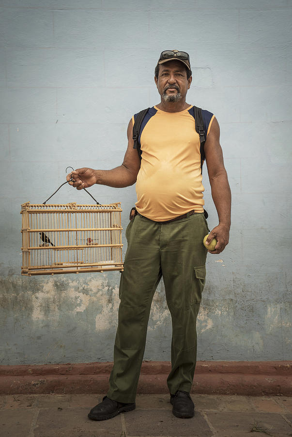 Man carrying caged pet bird Photograph by Buena Vista Images