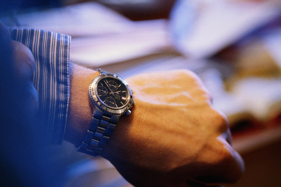 Man checking time on wrist watch, close-up Photograph by David De Lossy