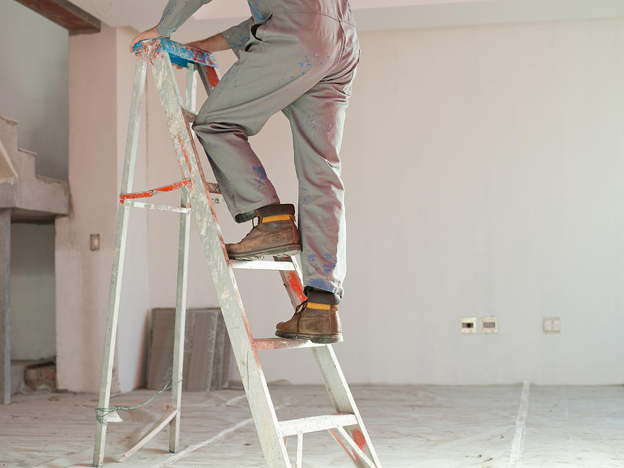 Man climbing ladder in unfinished room Photograph by Robert Daly
