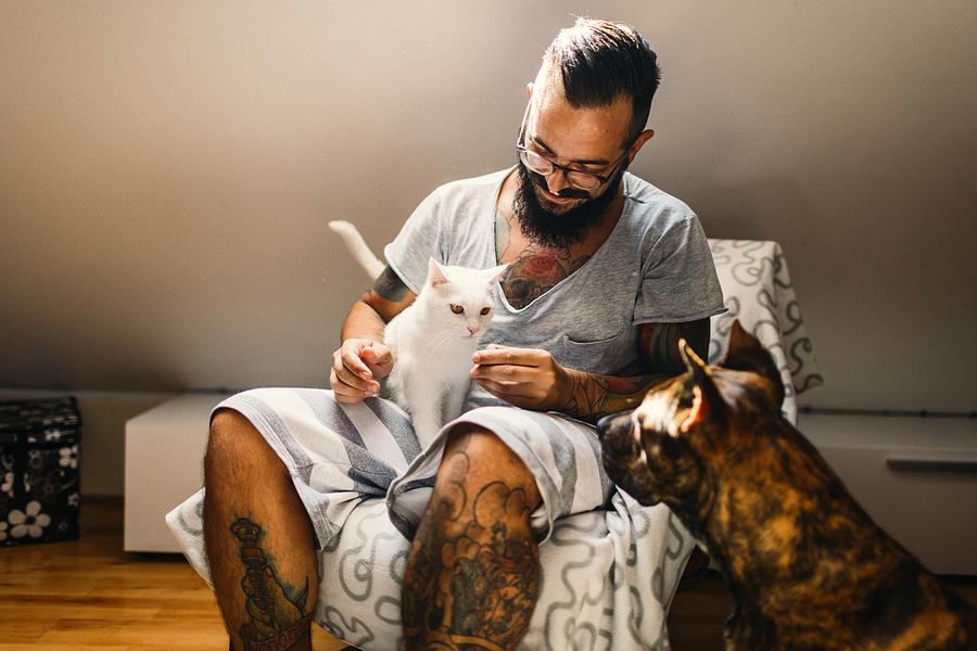 Man cuddling with his cat and his dog Photograph by Vgajic