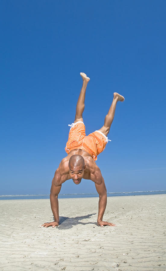Man does a handstand on beach. Photograph by Jim Arbogast