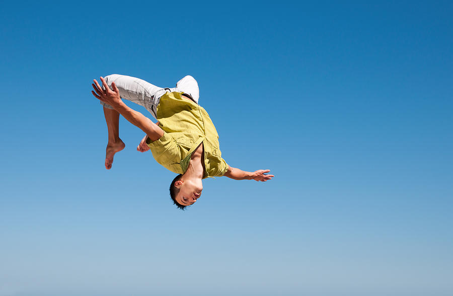 Man doing somersault in the air against blue sky Photograph by Sunnybeach