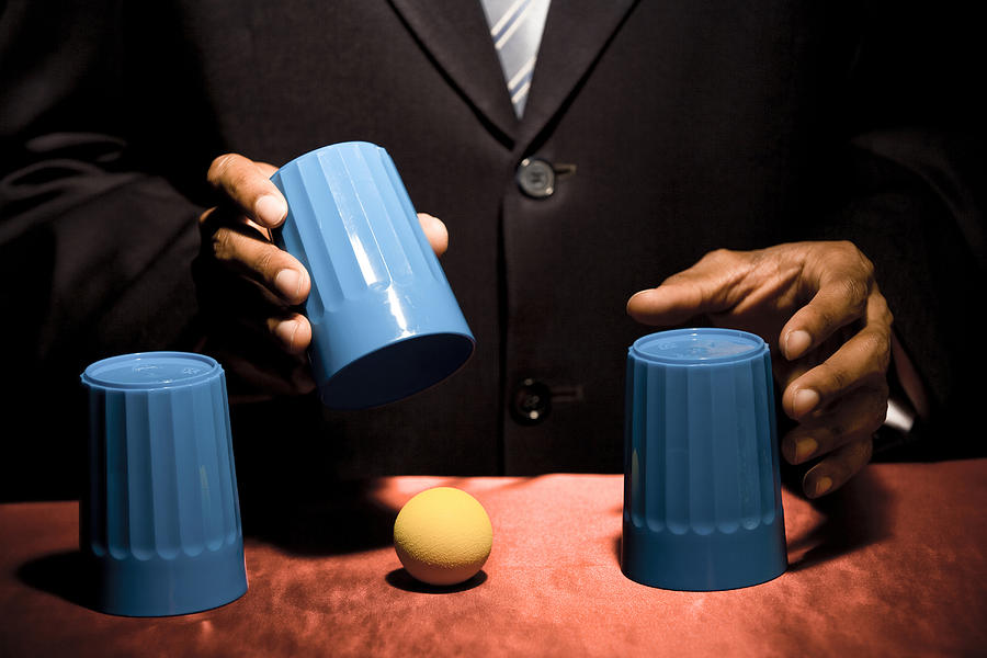 Man doing trick with three cups Photograph by Rubberball