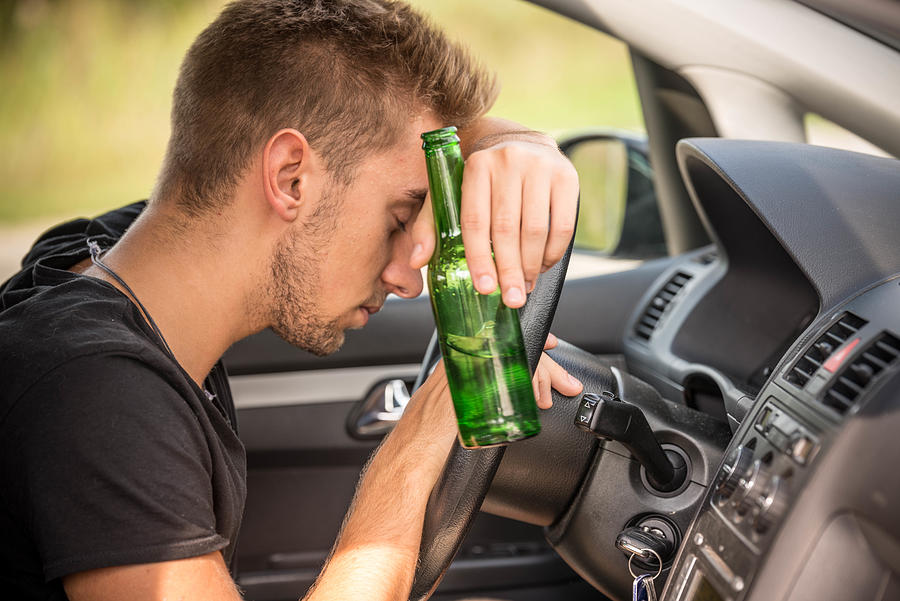 Man drinking beer while driving a car Photograph by Sestovic