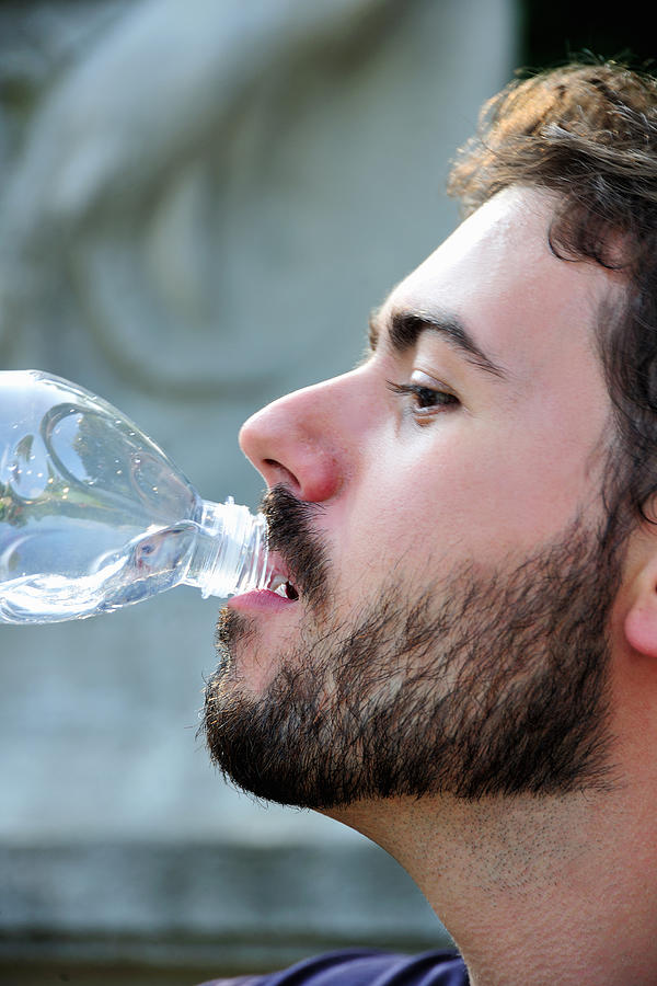 Man drinking from water bottle outdoors Photograph by Daniela Buoncristiani