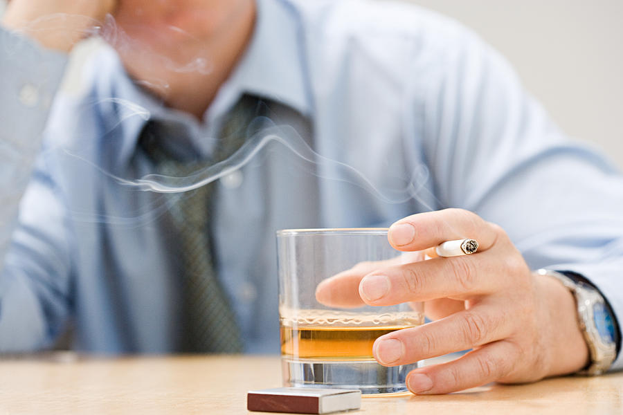 Man drinking whisky and smoking Photograph by Image Source