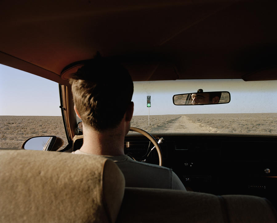 Man driving past traffic light on desert road, rear view, close-up Photograph by Matthias Clamer