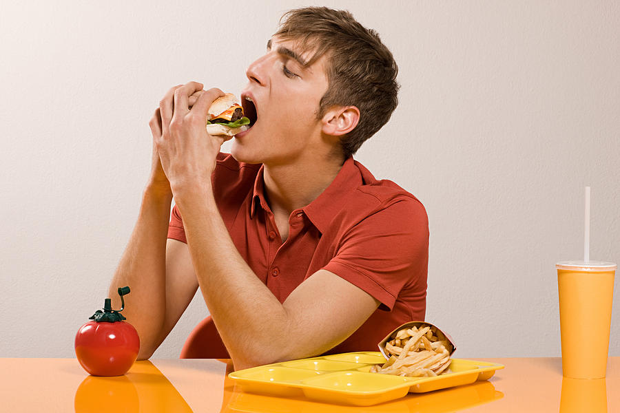 Man eating burger Photograph by Image Source
