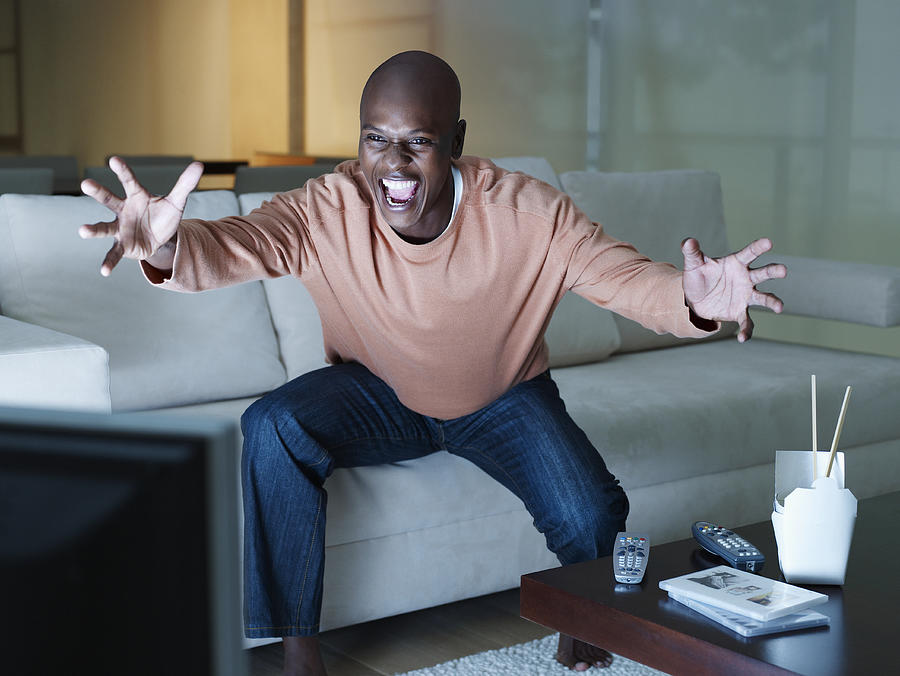 Man excitedly watching the television Photograph by OJO Images