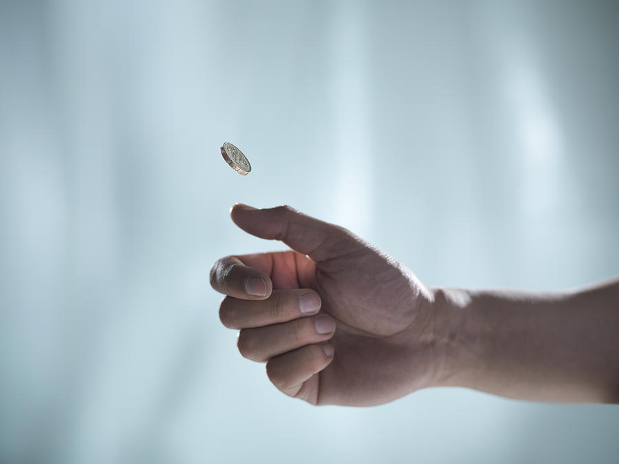 Man flipping one pound coin, pounds sterling Photograph by Monty Rakusen