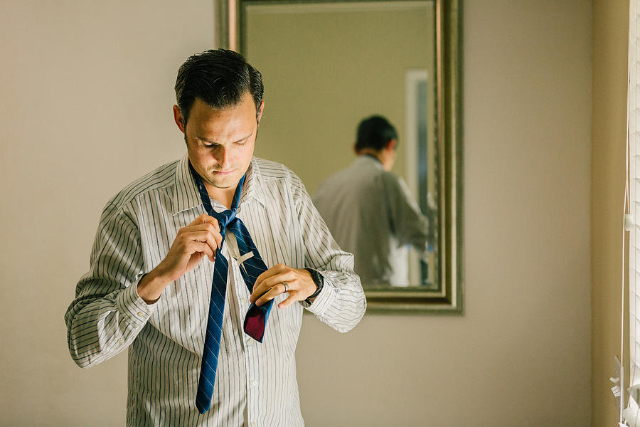 Man getting dressed, putting on neck tie Photograph by Heshphoto