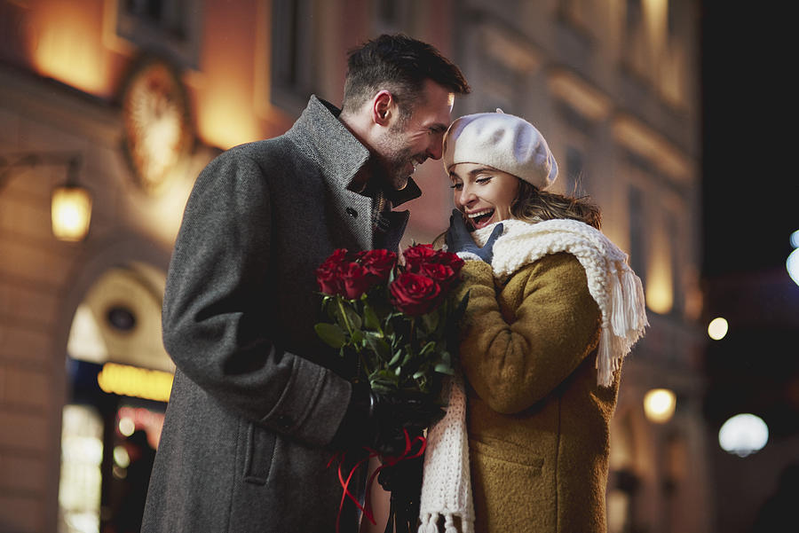 Man giving his amazed girlfriend bunch of red roses on Valentines Day Photograph by Westend61