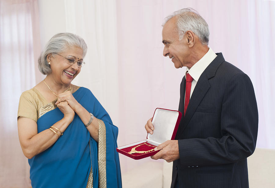 Man giving jewelry to his wife on their anniversary Photograph by Uniquely India