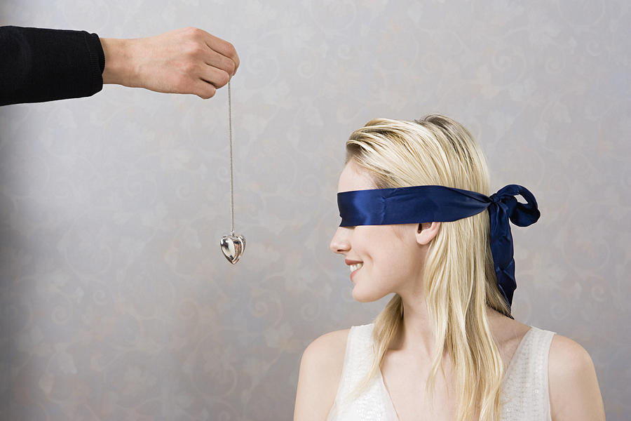 Man giving necklace to blindfolded woman Photograph by Image Source